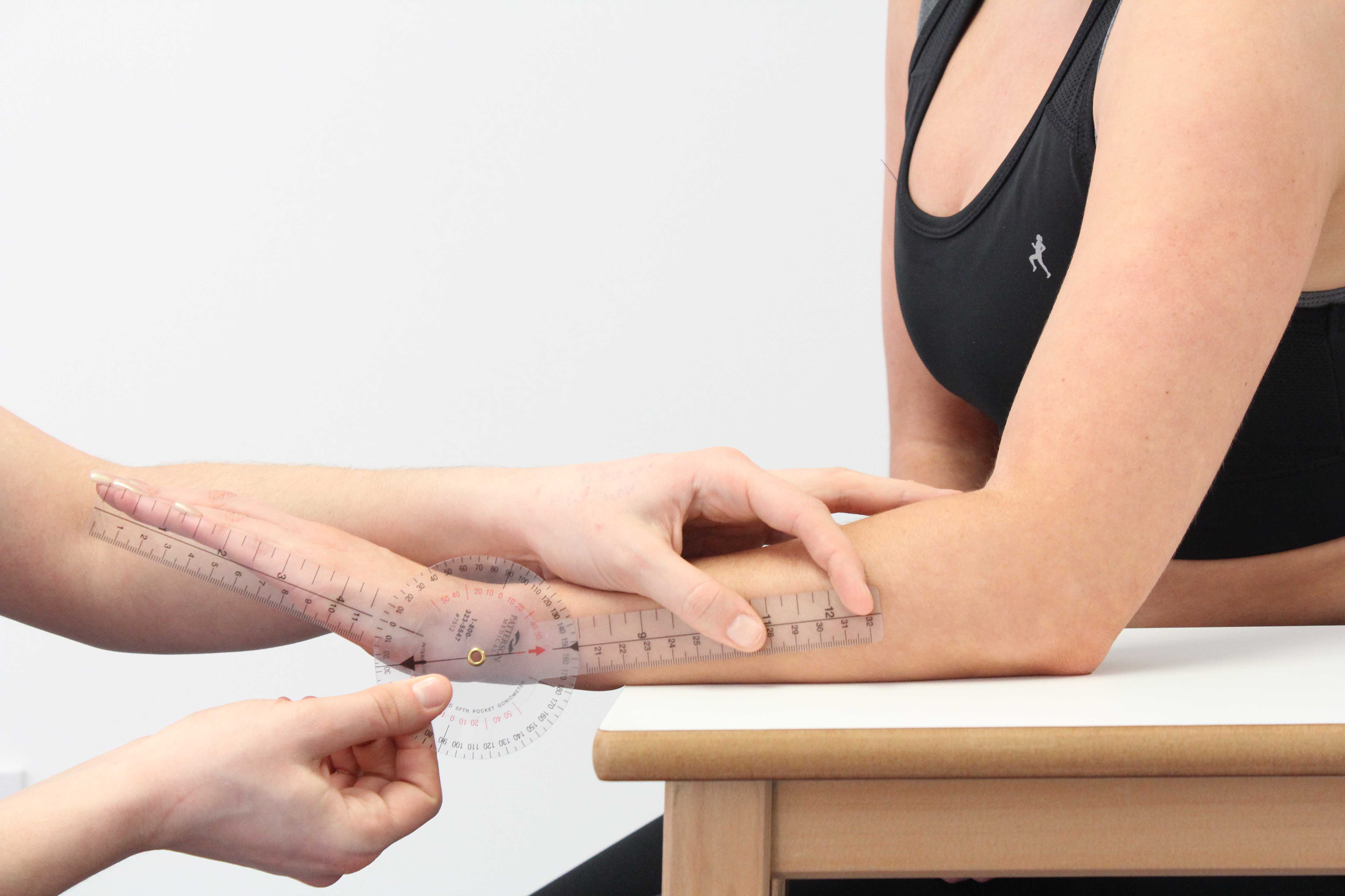 A physiotherapist monitoring a patients range of motion at the wrist.